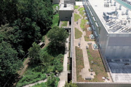 An aerial view of a large building surrounded by trees, with a green roof and a bioretention facility.