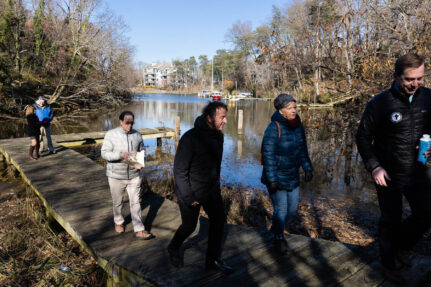 Group walks along a river in winter.