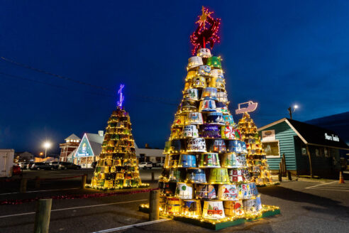 Crab baskets stacked on top of each other to form a tree, lit up with yellow Christmas lights.