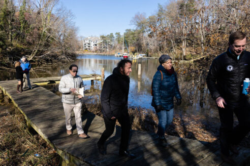 Group walks along a river in winter.