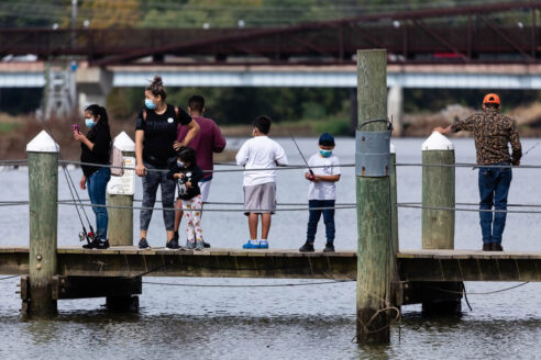 Group of people fish off a pier.