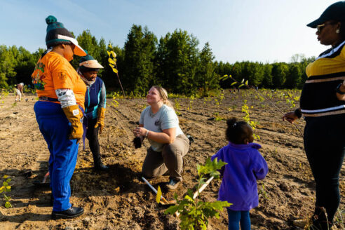 Volunteers gather to watch an instructor plant a tree