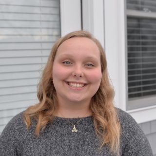 Caroline stands into front of a house.