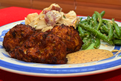 A plate with a blue catfish cake, potatoes, green beans.