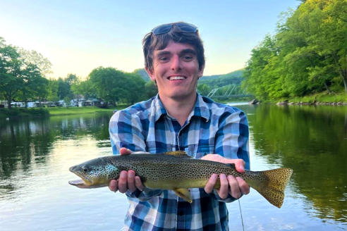 Keith is a white man wearing a blue shirt holding a fish.