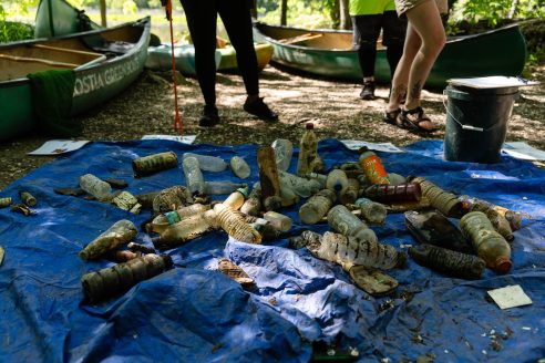 Plastic bottles emptied onto a blue tarp with people behind it.