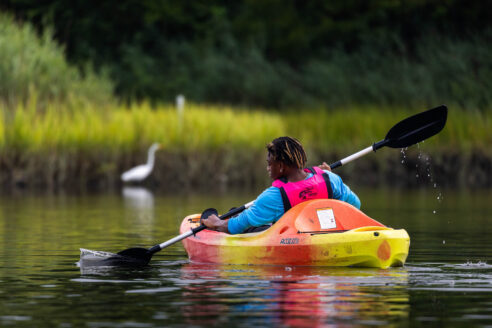 A young paddler navigates a wetland via kayak