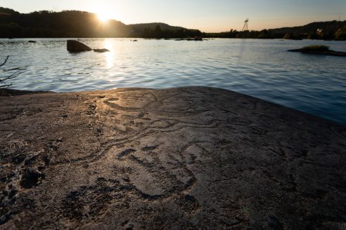 Rocks with carvings are seen next to the sun rising over the Susquehanna River