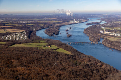 Aerial view of a river with forest and farmland on the side.