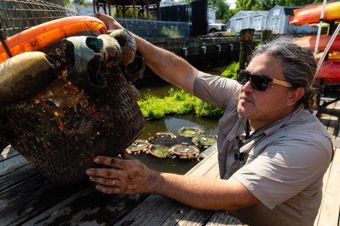 Jorge Bogantes Montero holds a basket of freshwater mussels on a dock.