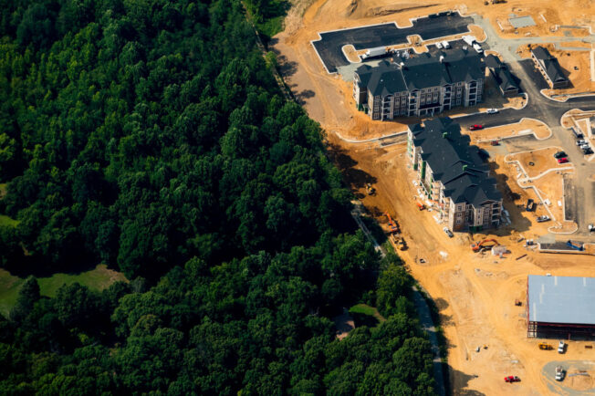 An aerial view of residential development encroaching on a forest.