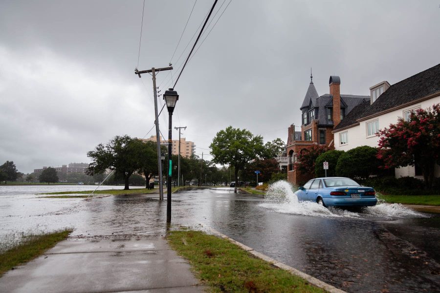 Flooded street with blue car driving through.