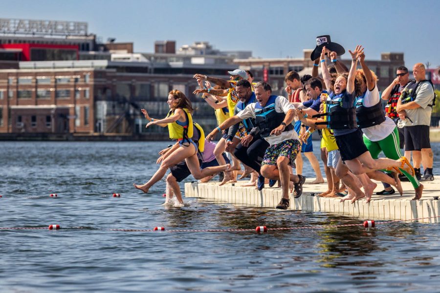 A large group of swimmers jumps in unison into open water.