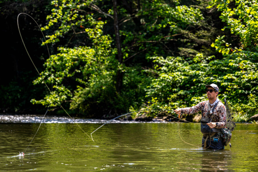 Man fly fishes in a wide stream.