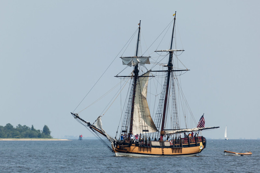 A tall ship in the water with white sails