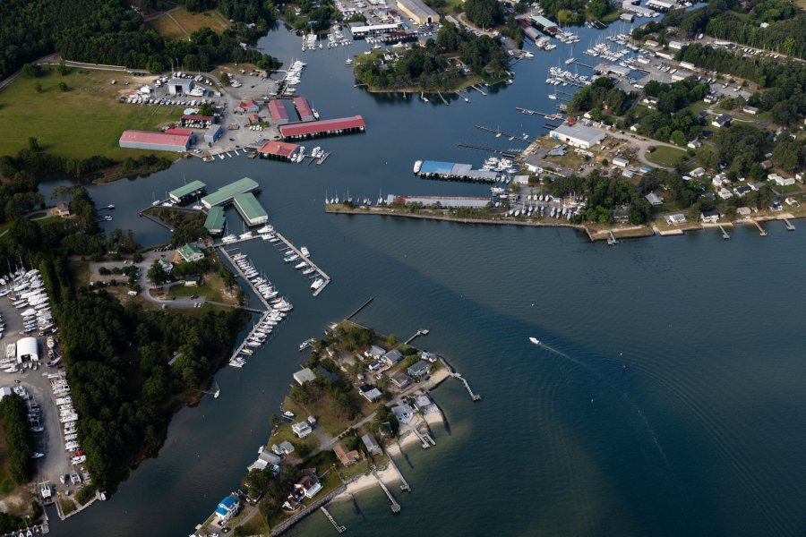 An aerial view of boat docks and local marinas bordered by a wooded landscape.