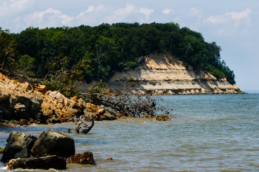 An eroding cliffside shows layers of sediment that have accumulated over time.