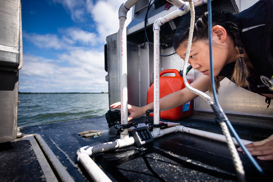 Student is on a boat looking at monitoring equipment.