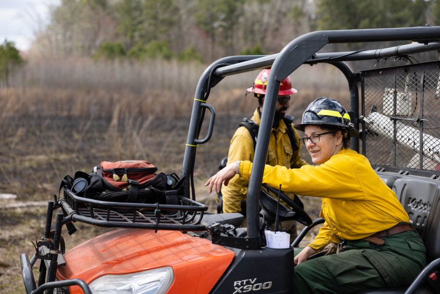 Landau sits in an off-road golf cart in front of a quiet, burned field.