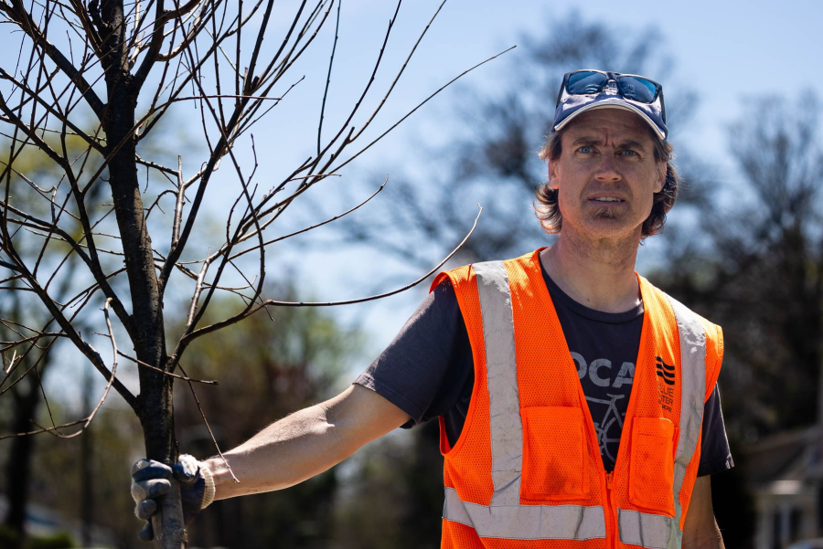 Darin, a white male, holds a tree recently planted.