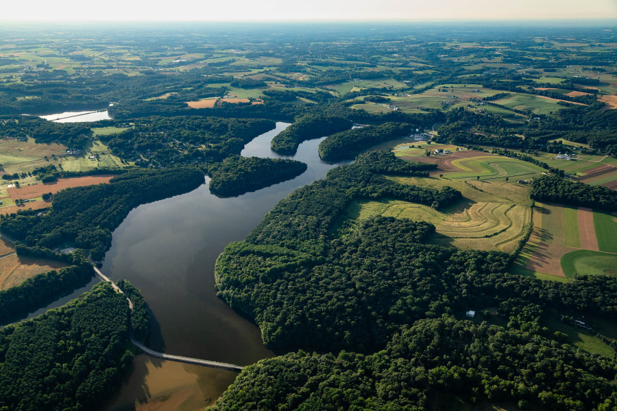 Aerial of the water with surrounding forest and farmland.