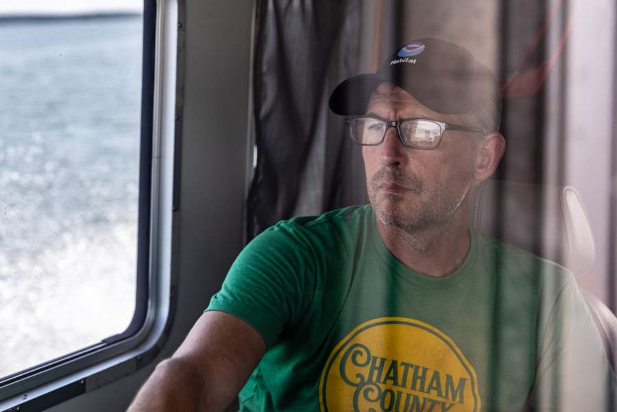 Jay Lazar looks toward the front of the boat, seen through reflections in the captain's window.