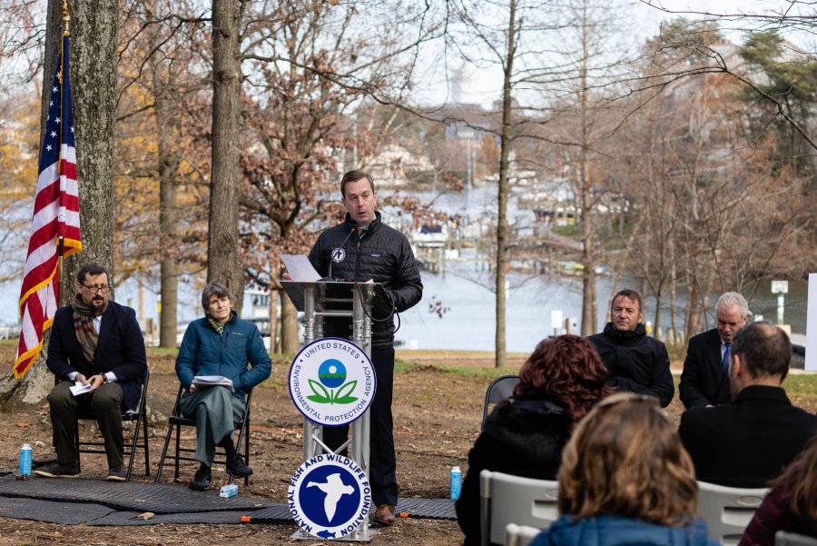 Jake stands on a podium, with a winter woods and river in the background.