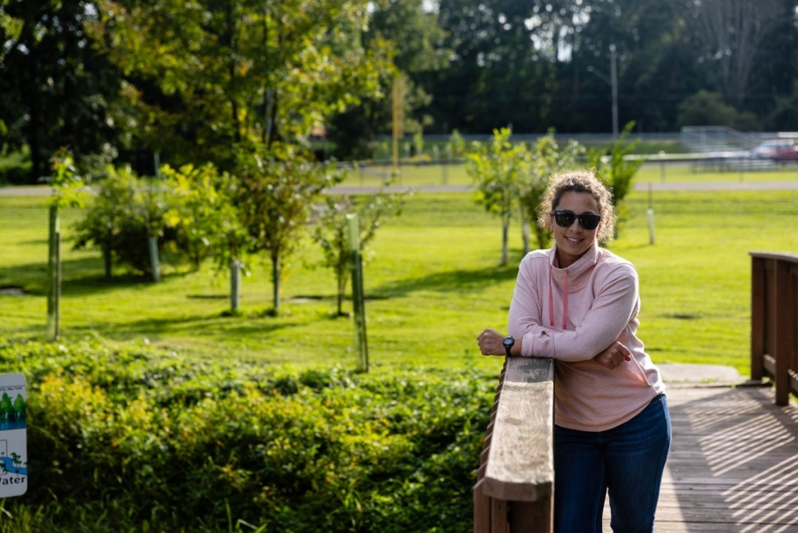 Lydia Brinkley stands on a wooden bridge. In the background is a field with small trees.