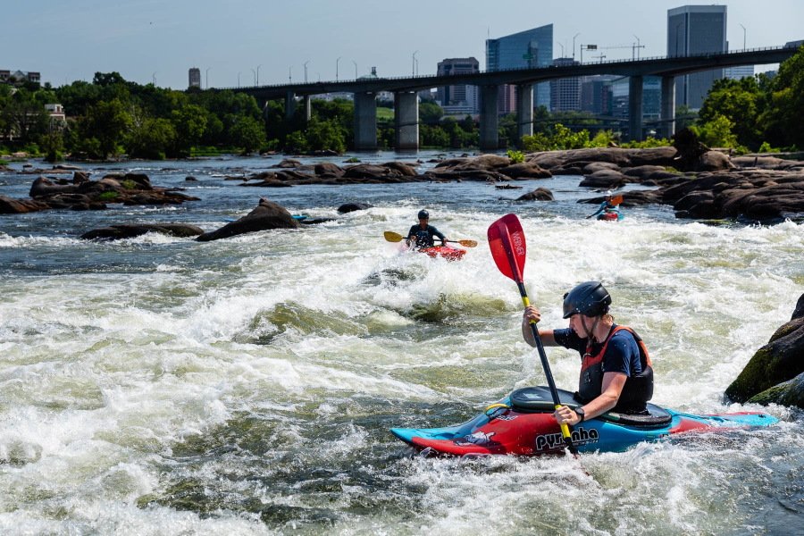 Kayakers paddle through rapids on the James River in Richmond, Va.