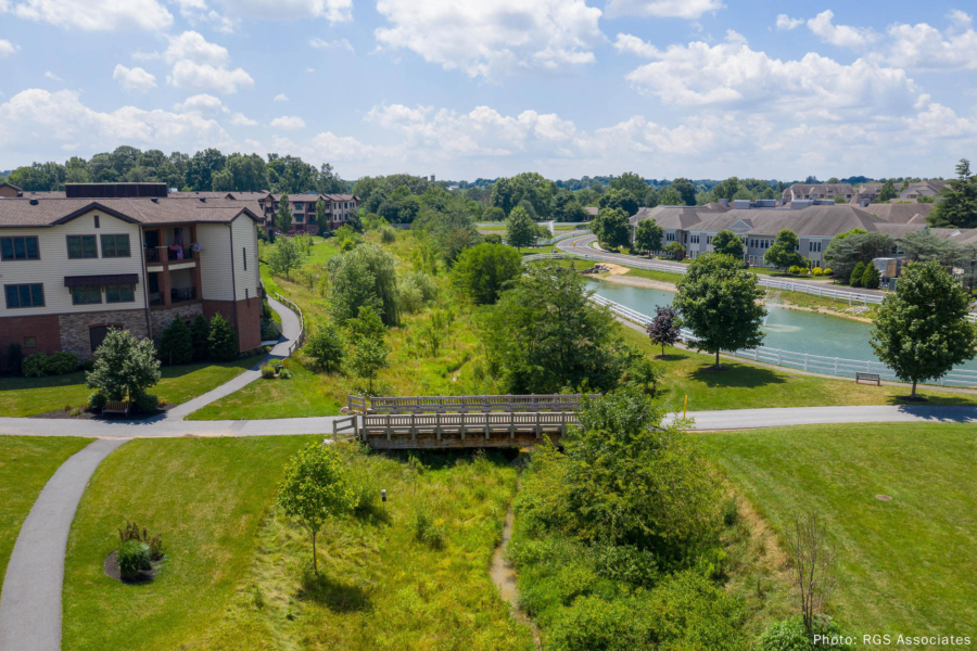 An aerial view of the Landis Homes retirement community shows Kurtz Run bordered by grasses, shrubs and trees.