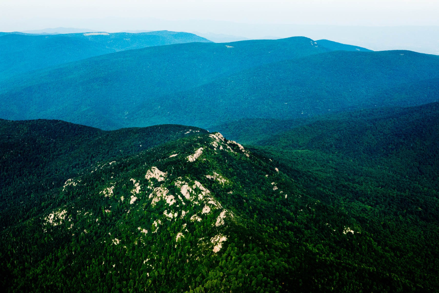 An aerial view of a forested and rocky mountain ridge.