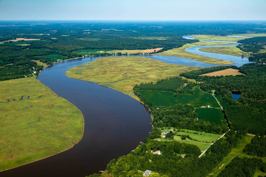 Aerial view of two rivers meeting with farmland and some housing development alongside them.