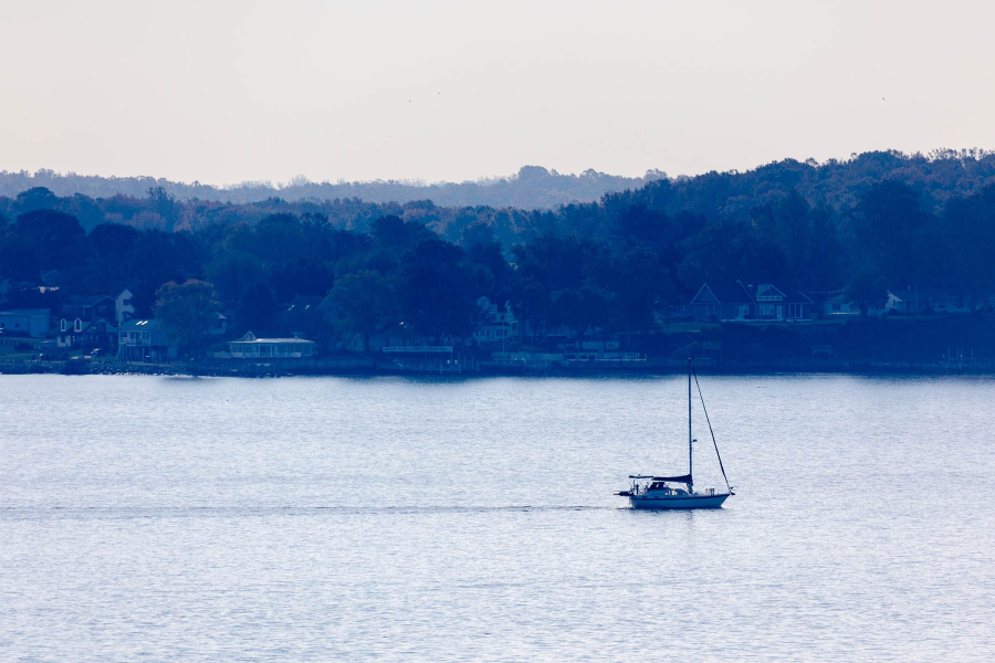 A sailboat is shown on the Chesapeake Bay with land in the distance.