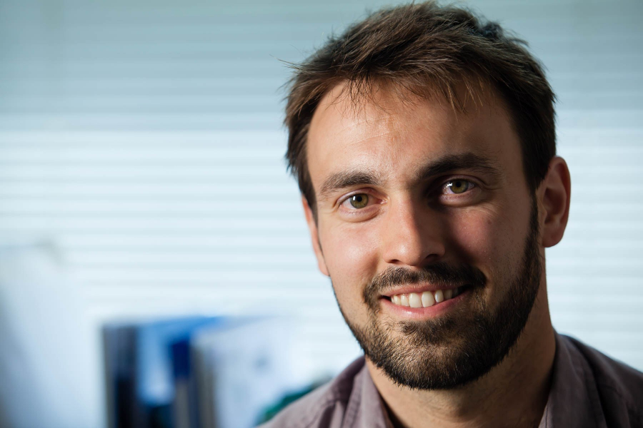 A headshot of Colin Christopher smiling in his office