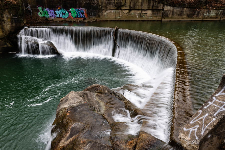 Penned in by a concrete wall, a curving waterfall drops ten feet.