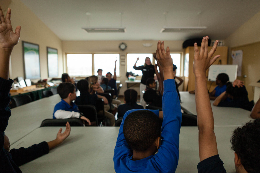 Students raise their hands in a classroom