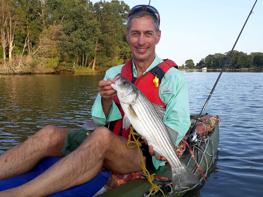 Peter Tango holds a rockfish he caught while sitting in his kayak.