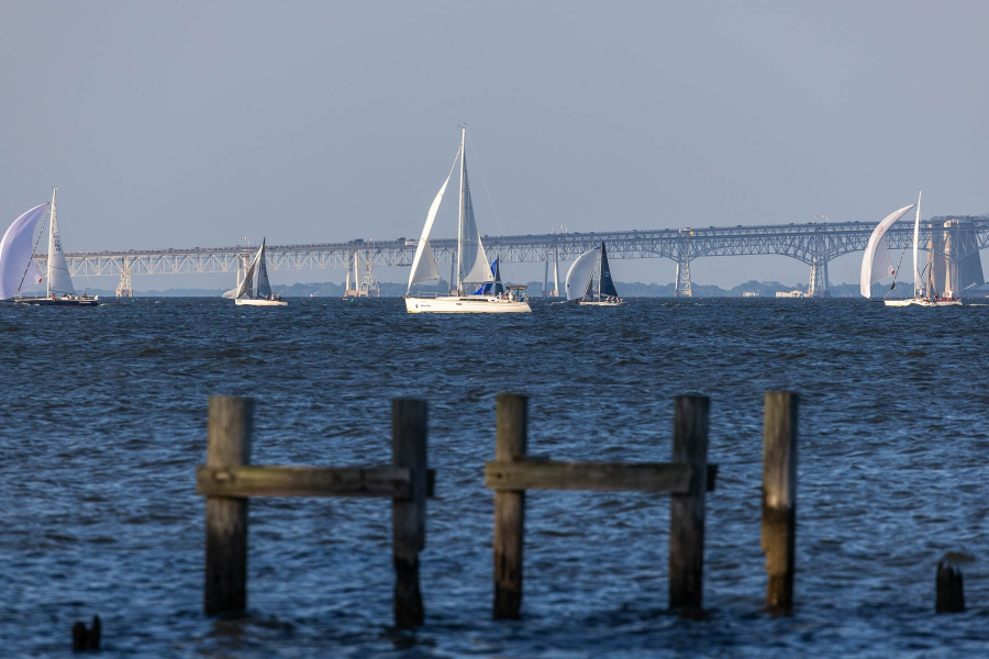 Sailboats are seen on the water with a bridge in the background