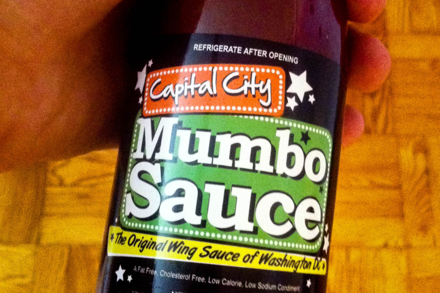 The label of a bottle says "Capital City Mumbo Sauce" with a tagline of "The original wing sauce of Washington, D.C."