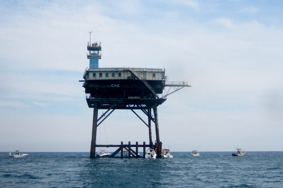 Chesapeake Light rises above the water, with fishing boats below the elevated "Texas tower" structure