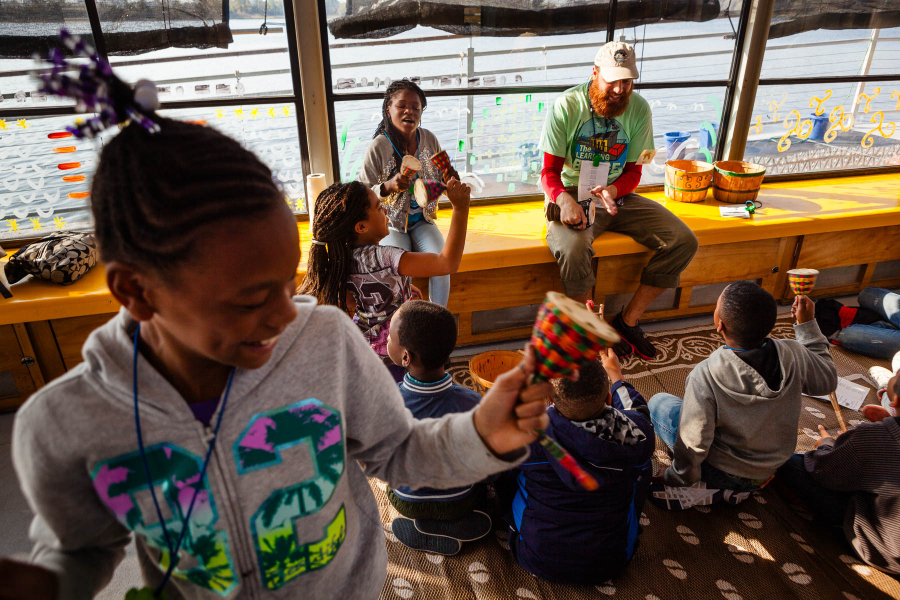 Student in foreground is a young black girl holds up a piece of art.