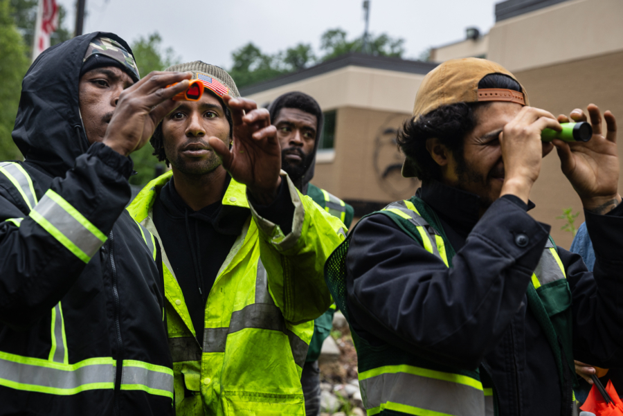 Charles reaches out to adjust a piece of equipment held by a crew member in front of his face.