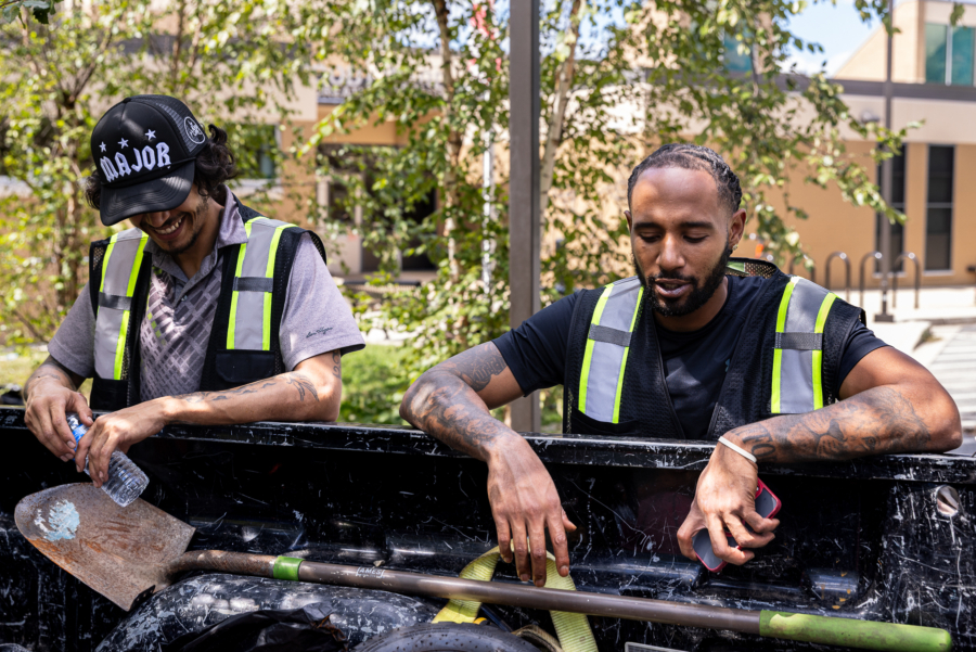 Charles rests on the bed of a truck while a crew member smiles